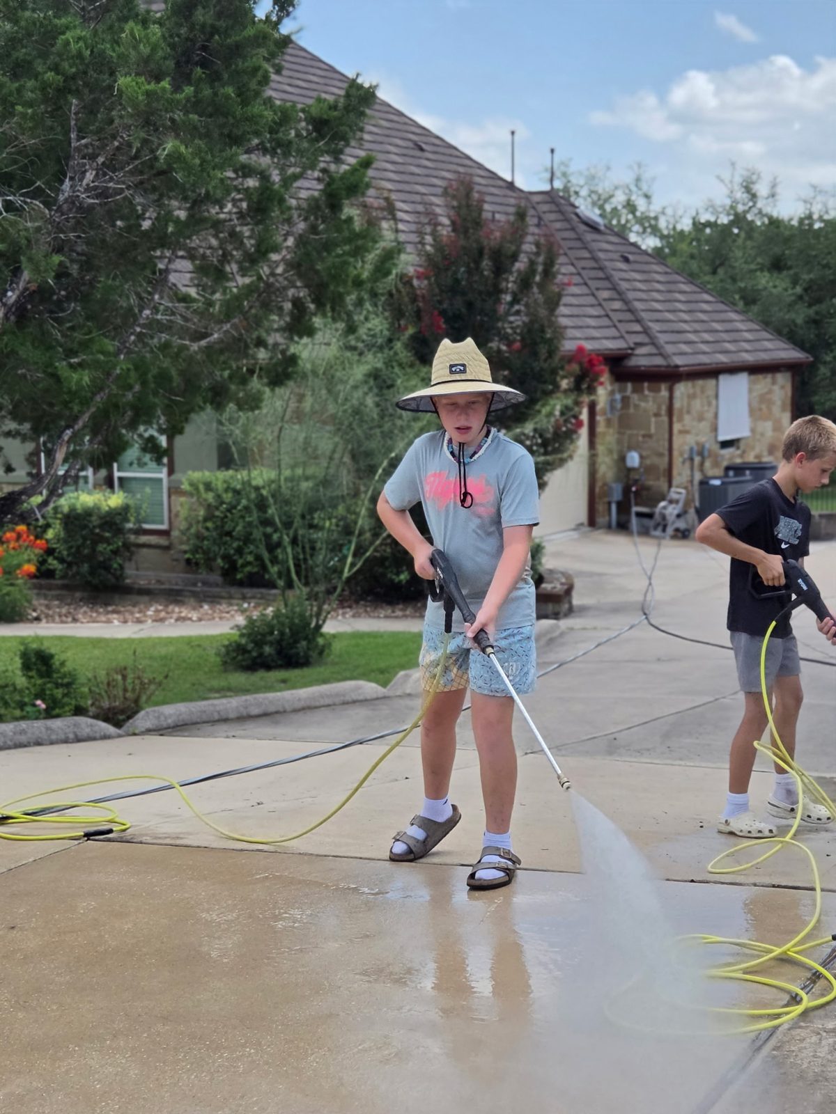 Liam and Jack of D1 Outdoor Services power washing a driveway in Austin 78737