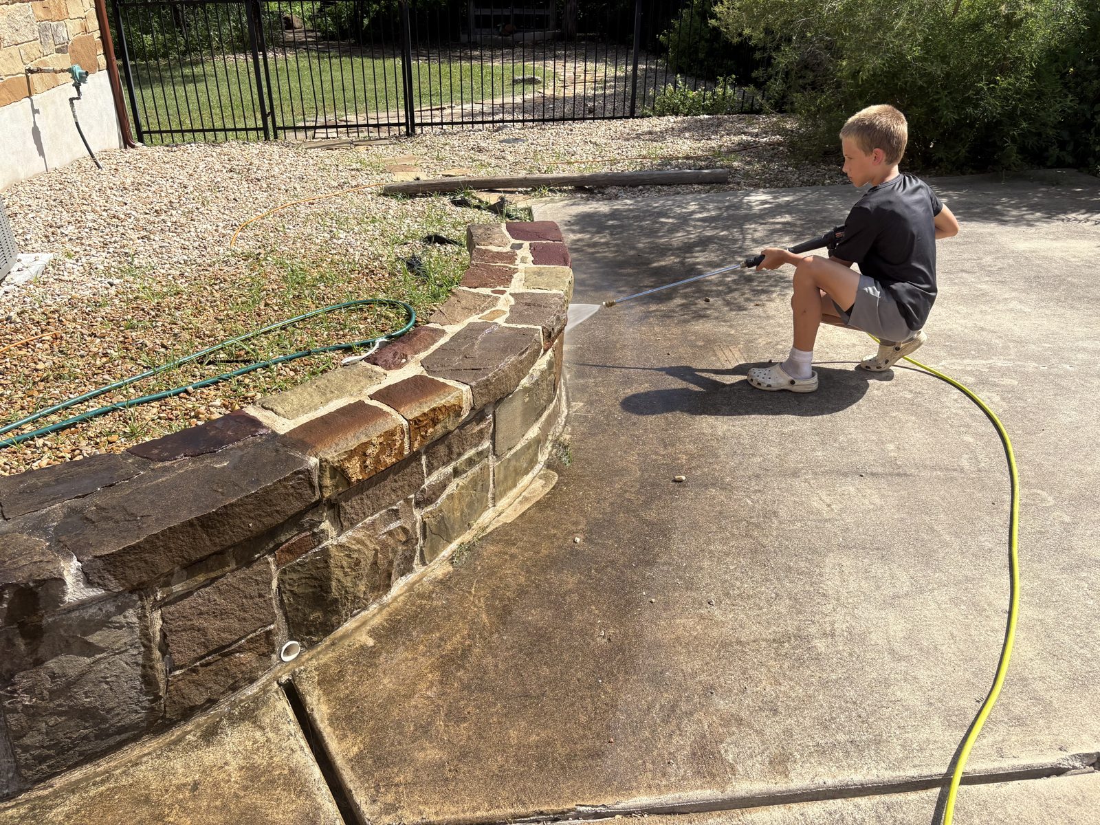 D1 Outdoor Services power washing a stone retaining wall